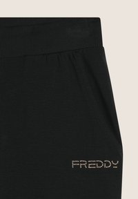 I jogger neri in cotone presentano un elastico in vita e una tasca laterale, adornata con borchie metalliche che formano il nome del marchio "FREDDY."