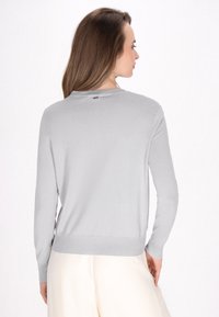 Pullover grigio chiaro a maniche lunghe con scollo rotondo e orlo a costine. Tessuto liscio con dettagli minimi, che mette in mostra un design semplice e moderno.