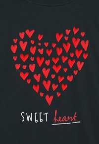 Black fabric with embroidered red hearts in various sizes forming a heart shape. Text "SWEET heart" in white and red below the design.