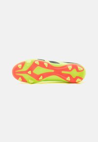 Botas de fútbol con una parte superior de un verde brillante, acentos en negro y una suela con un patrón en rojo y blanco para tracción en superficies de hierba.