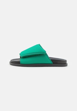 Groene slidesandaal met brede verstelbare band en zwarte zool, ontworpen om gemakkelijk aan te trekken.
