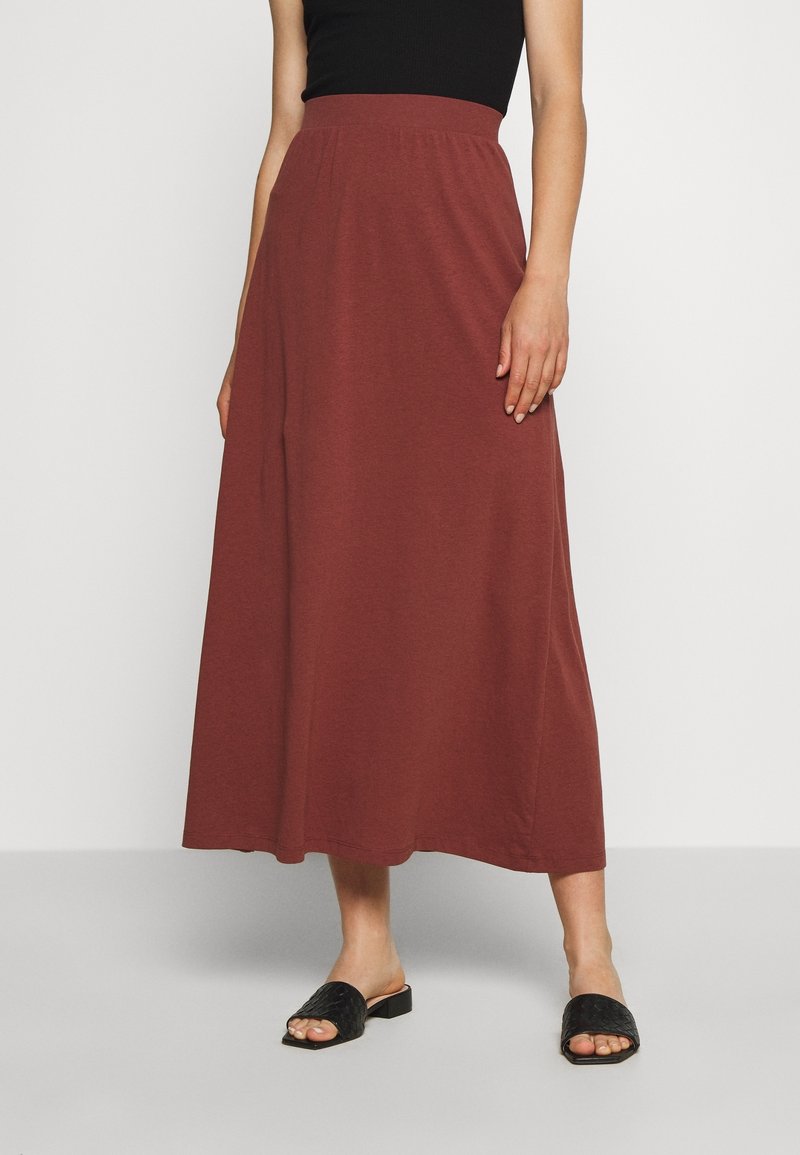 Jupe maxi bordeaux en tissu doux avec une taille élastique. Assortie à des sandales à enfiler noires et texturées. Design lisse et fluide.