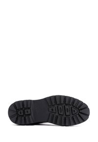 Suela de bota de goma negra con un diseño texturizado. Presenta patrones de relieve profundos para agarre y estabilidad. Material duradero para uso al aire libre.