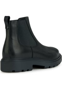 Botín Chelsea de cuero negro con paneles laterales elásticos, una lengüeta de tira y una suela de goma gruesa y texturizada. Acabado suave con una construcción duradera.