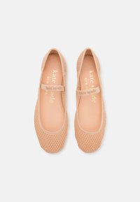 Peach-colored ballet flats with mesh overlay, round toe, and a Mary Jane strap. Gold logo printed on insole. Smooth texture.