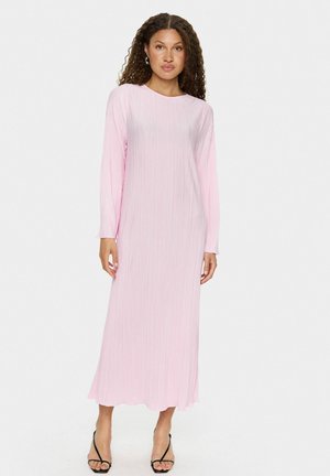Long-sleeve, pink dress with vertical pleats, round neckline, and flowing hem. Worn with black strappy heels, featuring a smooth texture.