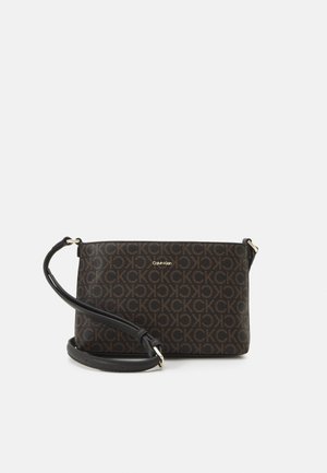 Sac bandoulière marron Calvin Klein avec motif répétitif du logo CK et sangle noire réglable sur fond uni.