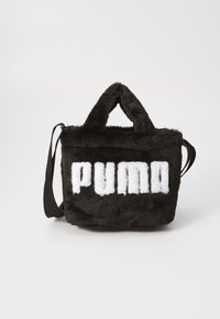 Svart pälsväska med "PUMA" i vit text. Den har dubbla handtag och en avtagbar axelrem. Materialet verkar mjukt och plyschigt.