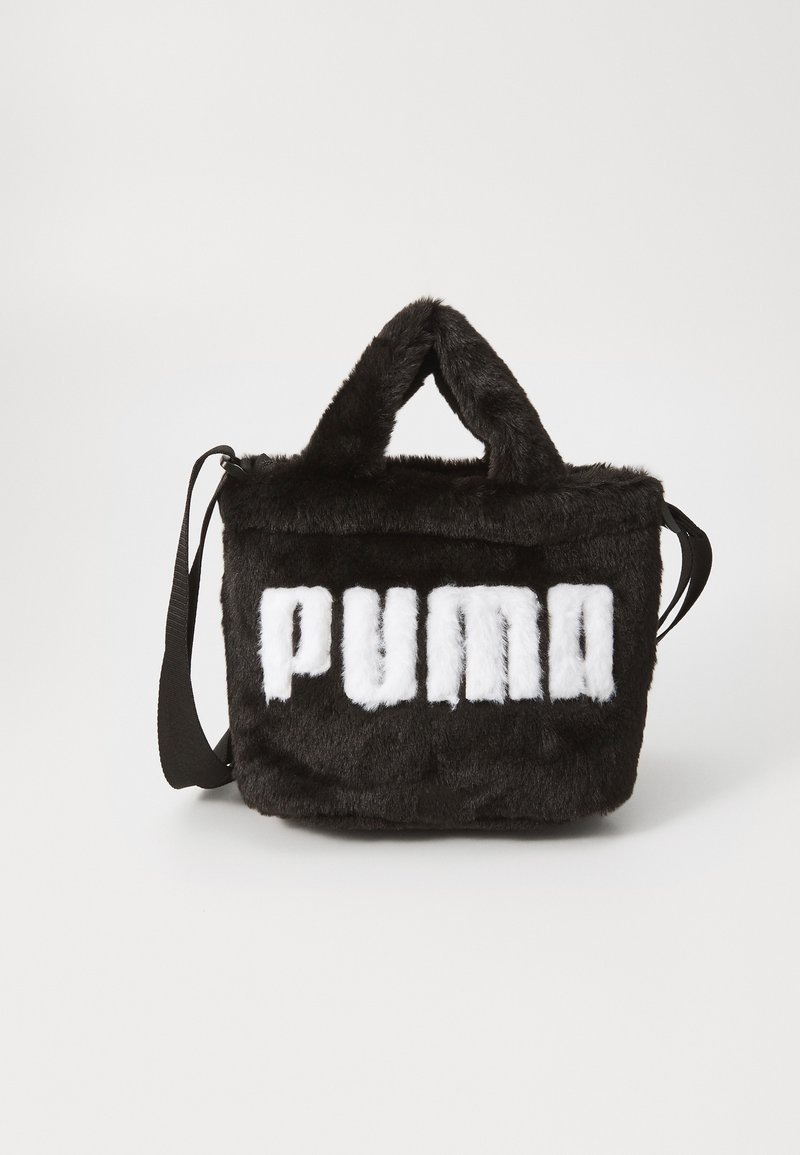 Svart pälsväska med "PUMA" i vit text. Den har dubbla handtag och en avtagbar axelrem. Materialet verkar mjukt och plyschigt.