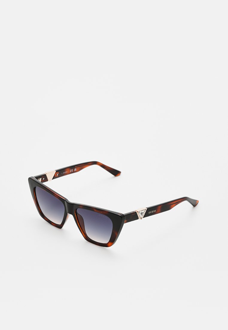 Lunettes de soleil en écaille de tortue avec une monture géométrique, des verres dégradés et des accents en métal portant un logo sur les branches.