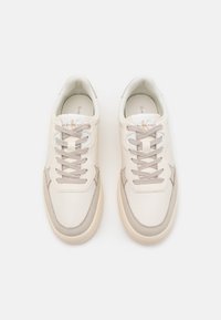 Sneakers in pelle beige con accenti grigi, punta rotonda e lacci. Interno imbottito e branding sottile sulla linguetta. Texture liscia.