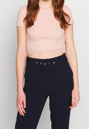 Top corto rosa chiaro con maniche corte, texture a costine e bordi in pizzo all'orlo, abbinato a pantaloni a vita alta blu scuro con cintura.