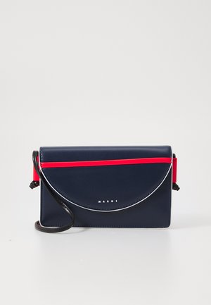 Borsa a tracolla in pelle blu navy con patta rotonda, striscia di accentuazione rossa e ferramenta in argento. Presenta una tracolla staccabile e dettagli con logo.