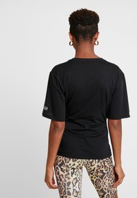 Czarna koszulka z krótkim rękawem wykonana z bawełny, o luźnym kroju. Posiada małe logo na rękawie. W zestawie z legginsami w wzór z motywem zwierzęcym.