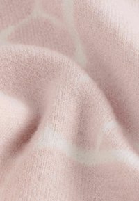 Jemná ružová tkanina s hladkou textúrou, ktorá obsahuje jemný biely geometrický vzor. Materiál je ľahký a mierne chlpatý.