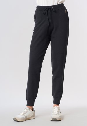 Pantaloni jogger neri in materiale morbido, con vita con coulisse, gambe affusolate e un piccolo dettaglio logo sull'anca sinistra.