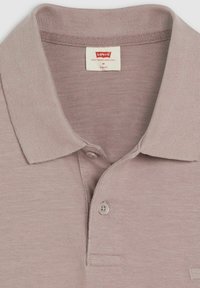 Ljus mauve polo skjorta med krage, korta ärmar, knappslå och en liten bröstficka. Tillverkad av mjukt, strukturerat tyg.