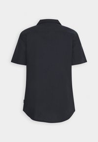 Maglietta a maniche corte in tessuto nero uniforme; presenta un colletto classico, vestibilità comoda e orlo curvo con un'etichetta laterale vicino al fondo.