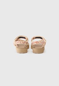 Tan sandals with patterned straps in pink and orange. Features a thick sole and adjustable ankle straps for secure fit.