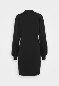 Černé dlouhé šaty s nafouklými rukávy a přiléhavými manžetami, zobrazené ze zadní strany na jednobarevném světle šedém pozadí.