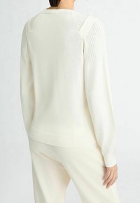 Pletený svetr z měkké bílé látky, s žebrovanými detaily na ramenou a rukávech, volný střih a žebrovaný lem.