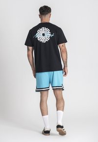 Camiseta de algodón negra con un gráfico blanco en la parte posterior y shorts deportivos de color azul claro con franjas negras y blancas en el dobladillo.