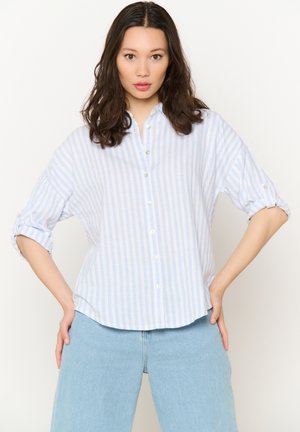 Light blue and white striped button-up shirt with a collar, rolled sleeves, and soft fabric; paired with high-waisted denim jeans.