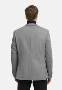 Blazer grigio con vestibilità su misura, tessuto testurizzato, rever a punta e uno spacco sul retro. Design minimalista con polsini abbottonati.