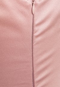 Svetle růžová, strukturovaná tkanina s hladkým povrchem, se zapínáním na zip a švy podél strany.