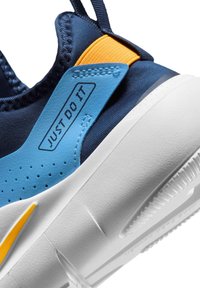 Κοντινή λήψη της φτέρνας αθλητικού παπουτσιού σε ναυτικό μπλε και κίτρινο χρώμα με λευκή σόλα, με το κείμενο «JUST DO IT» σε μπλε δερμάτινη λεπτομέρεια.