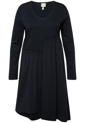 Dlouhé černé šaty s výstřihem do V, detaily v oblasti pasu s řasením a asymetrickým lemem. Vyrobeno z měkké tkaniny pro pohodlí.