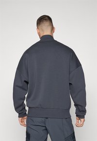 Dunkelgrauer Sweatshirt mit Rundhalsausschnitt in lässiger Passform, gerippten Bündchen und Saum sowie weicher Textur. Verfügt über überschnittene Schultern für einen lockeren Look.