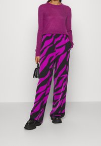 Svarta byxor med vida ben och djärva magenta zebramönster. Matchas med en fluffig magenta tröja och kraftiga svarta plattformsskor.