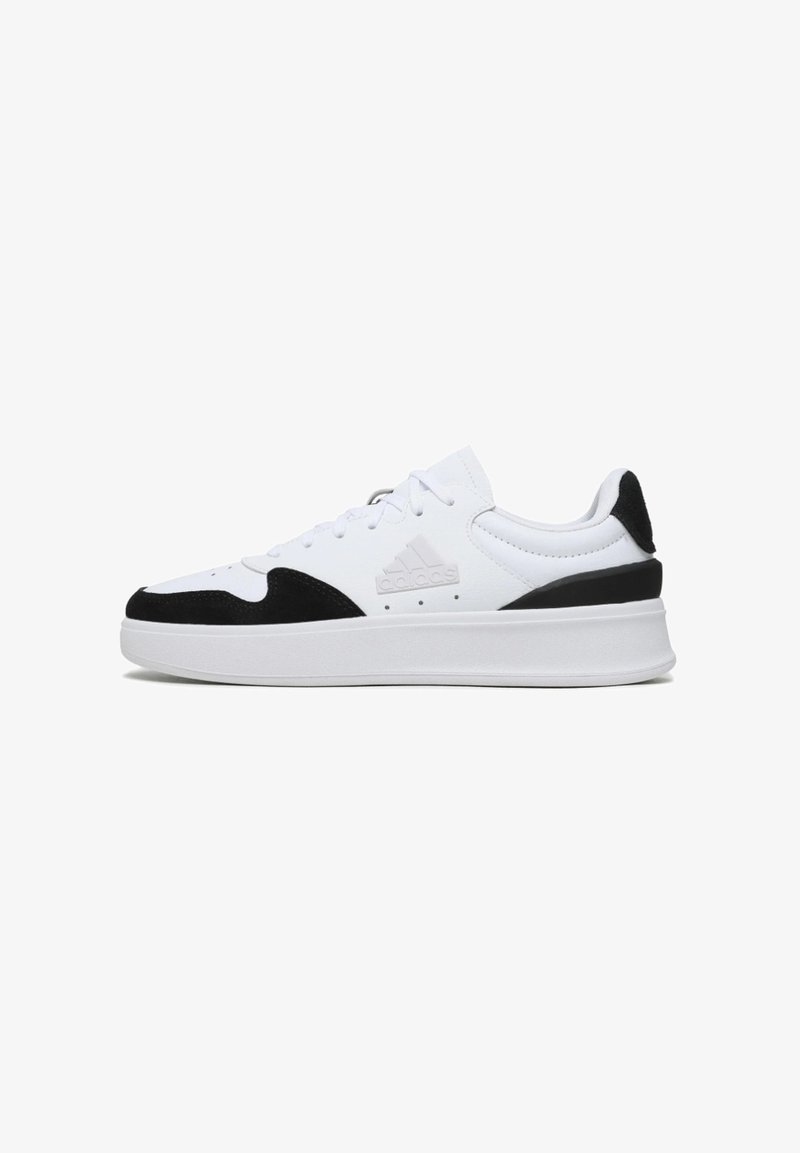 Zapatillas deportivas blancas con detalles en ante negro, que cuentan con un diseño de cordones, cuello acolchado y una suela gruesa blanca.