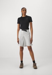 Chemise noire à manches courtes, shorts gris avec une ceinture et chaussures de randonnée brunes. Texture lisse et design fonctionnel adapté aux activités de plein air.