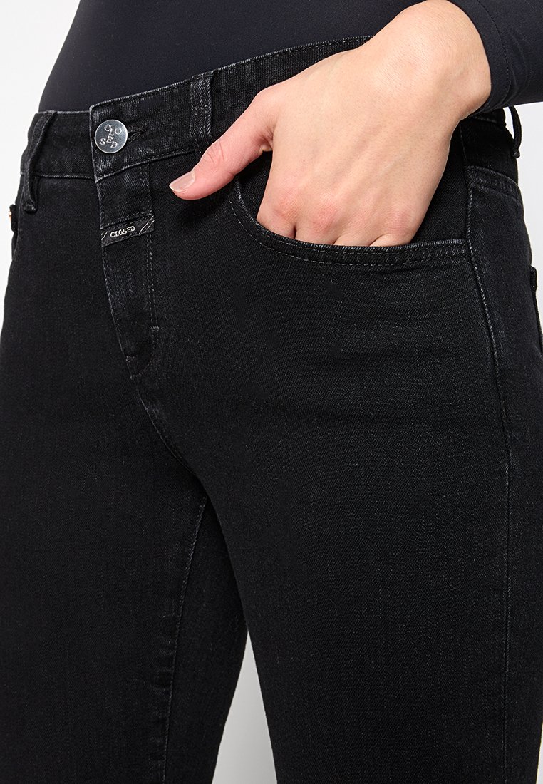 Schwarze Denim-Jeans mit einer taillierten Passform. Verfügt über einen Metallknopfverschluss, Gürtelschlaufen und Taschen. Glatte Textur mit dezenten Nahtdetails.