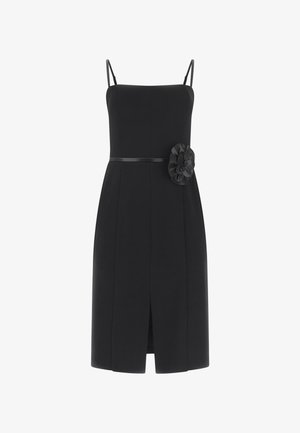 Abito nero senza maniche, lungo fino al ginocchio, con spalline sottili, vita aderente, spacco frontale e grande fiore in tessuto sul lato destro.