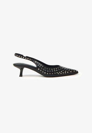 Sandal con tacco kitten a punta nera e cinturino, decorata con borchie argentate che coprono la parte superiore e il cinturino, esposta su uno sfondo bianco.