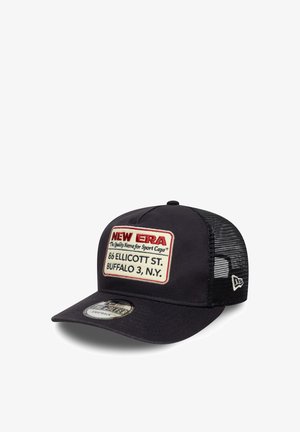 Schwarze Trucker-Cap mit strukturiertem Frontteil, Netzrücken und rotem Patch, auf dem "NEW ERA" sowie Standortdetails zu sehen sind. Mit gebogenem Schirm und Snapback-Verschluss.