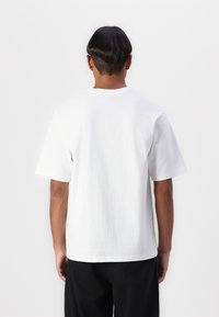 White cotton t-shirt with short sleeves, a round neck, and a straight cut. Smooth texture and no visible logos or patterns.