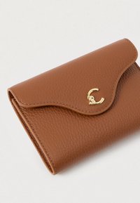 Bruine gestructureerde leren portemonnee met een gebogen klep en een kleine gouden interlock metalen accent op een witte achtergrond.