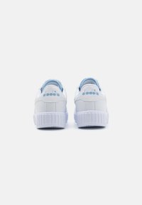 Zapatillas blancas con acentos en azul claro, que cuentan con un talón texturizado, parte superior sintética suave y una suela de goma con bordes estriados.