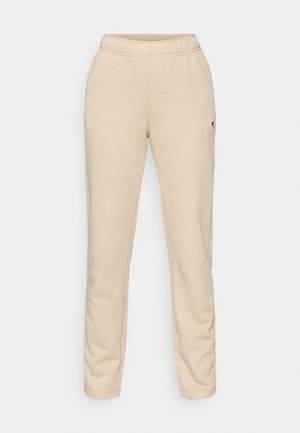 Bež trenirka od mekanog tkanja, s elastičnim pojasom i malom logotipšom zakrpom na lijevom bedrima. Uže pristajanje s suženim nogavicama.