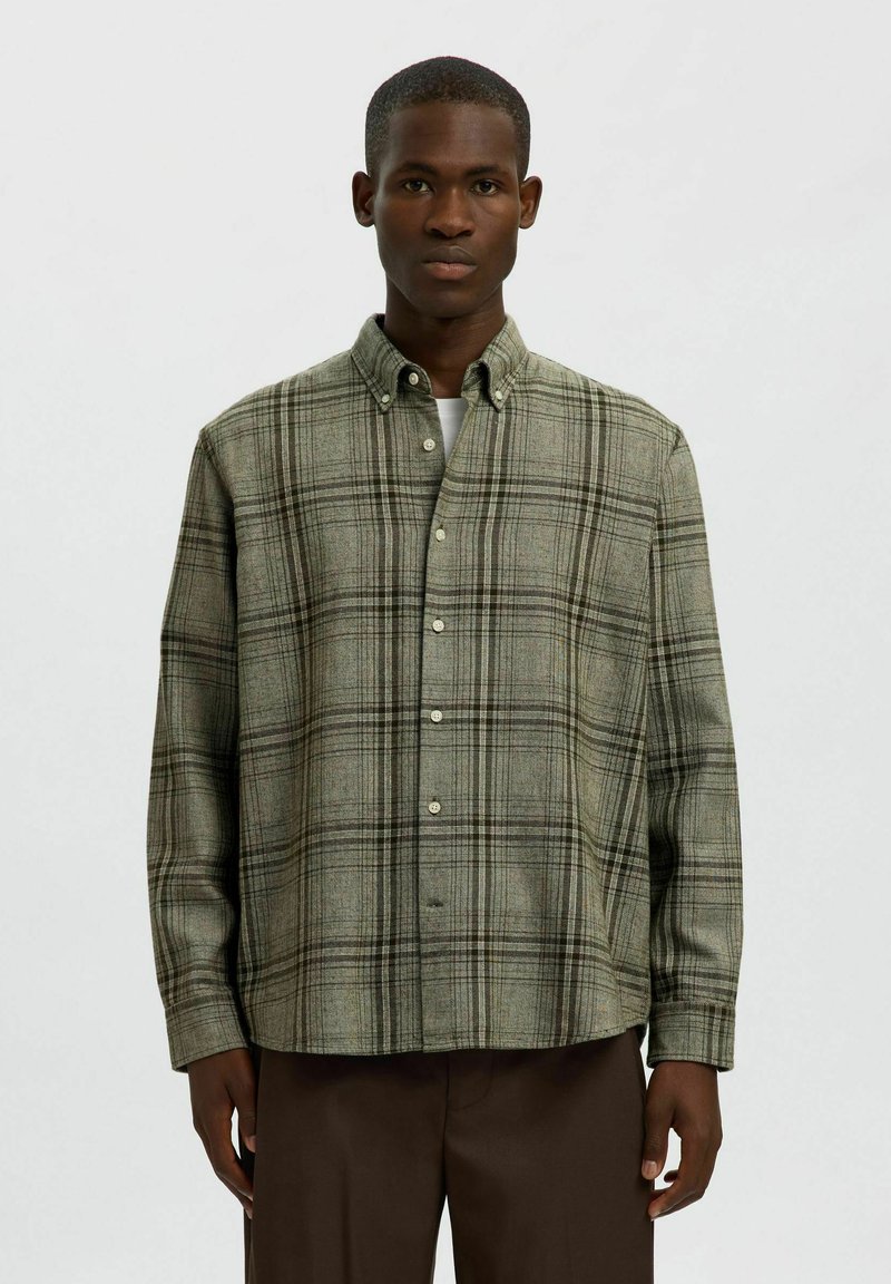 Zelena karo srajca s sprednjim gumbom iz strukturirane tkanine; ima gumbnico na ovratniku in dolge rokave, sproščen kroj ter skrite gumbe.