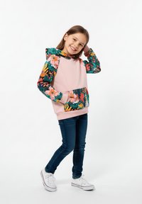Różowa bluza z kapturem z rękawami i kieszenią w kwiatowy wzór, zestawiona z ciemnoniebieskimi dżinsami i białymi trampkami. Gładka tkanina o intensywnych kolorach.