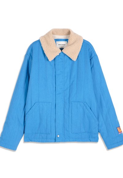Veste bleue avec col sherpa beige, deux poches avant, fermeture par boutons-pression et petit patch logo orange sur la manche gauche.