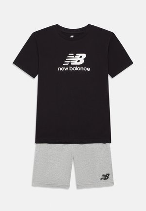 Crna majica s kratkim rukavima New Balance s bijelim logotipom i tekstom, uparena sa svijetlosivim kratkim hlačama s malim crnim New Balance logotipom.