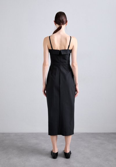 Black midi dress with thin straps, square neckline, fitted bodice, pleated details, and a straight hem. Material appears smooth and structured.