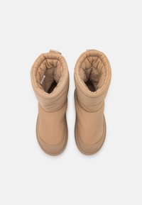 Brązowe, ocieplane buty z haftowanym wzorem, z miękkim wykończeniem wewnętrznym, zaokrąglonym czubkiem i delikatnym materiałem zewnętrznym. Elastyczny mankiet u góry dla lepszego dopasowania.