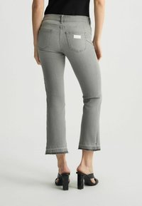 Šedé džíny z denimu s přiléhavým střihem, roztrhaným lemem a detaily na zadní kapse. V kombinaci s černými sandals na platformě featuring block heels.